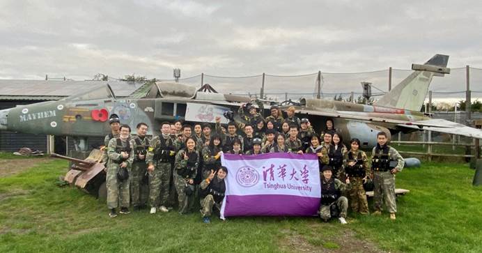 A group of people posing for a photo in front of a military planeDescription automatically generated with medium confidence